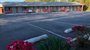 A motel with a parking lot and green doors. - Bassett Motel (Williamsburg)