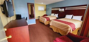 A hotel room with two beds, a desk, a television, and a window. - Bassett Motel (Williamsburg)