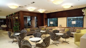 A modern lobby with a central seating area, a reception desk, and a large window with a view. - Hotel Metropolitano Supara (Buenos Aires)