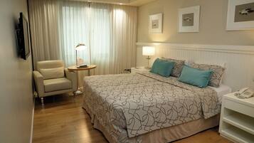 Una habitación de hotel con cama, una silla, mesita de noche, lámpara y teléfono.