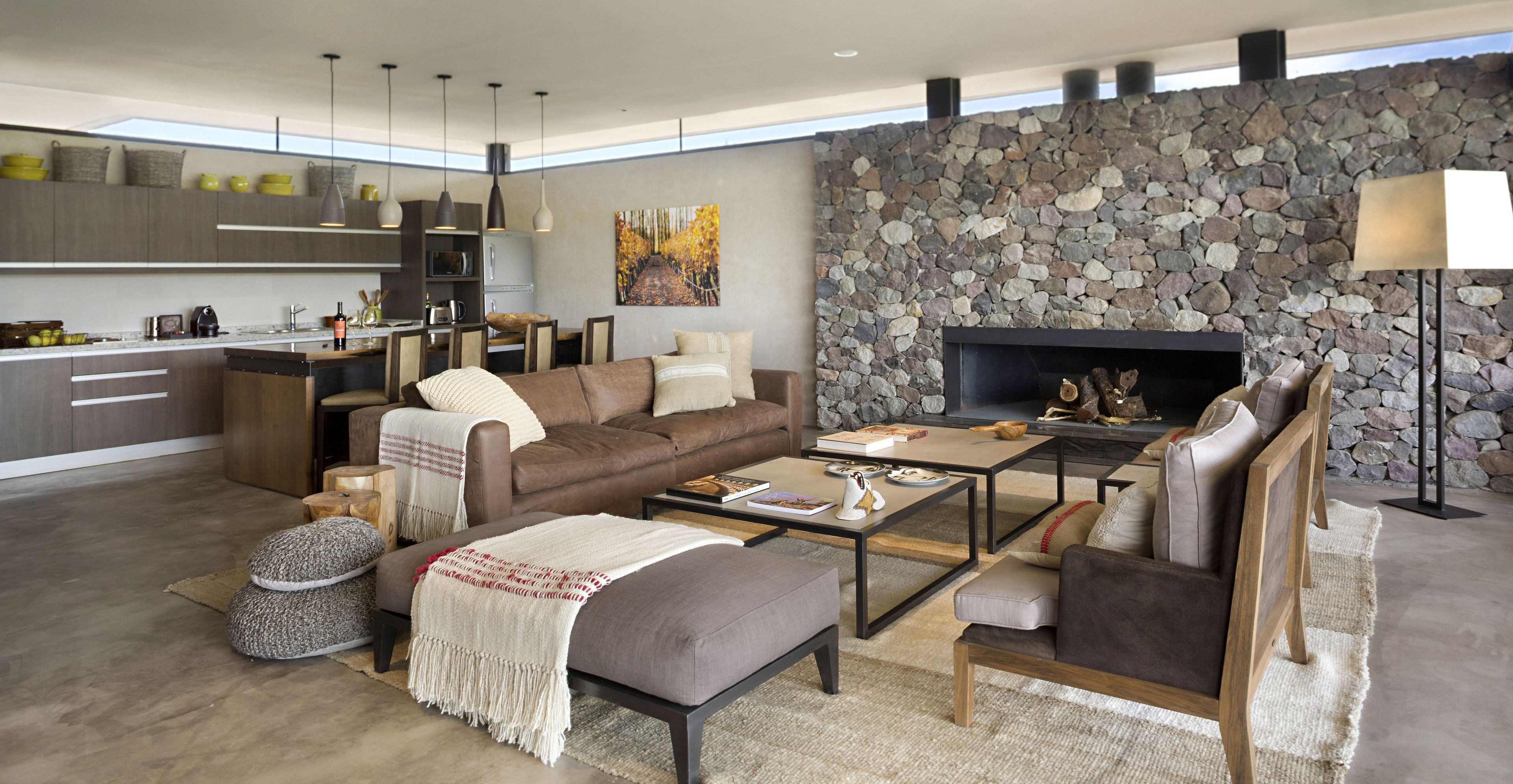 Un espacio habitable moderno con cocina, comedor y zona de estar, que cuenta con una pared de piedra y chimenea.
