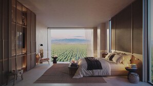 Un dormitorio con un ventanal grande, una cama, una mesita de noche y vistas a un viñedo.