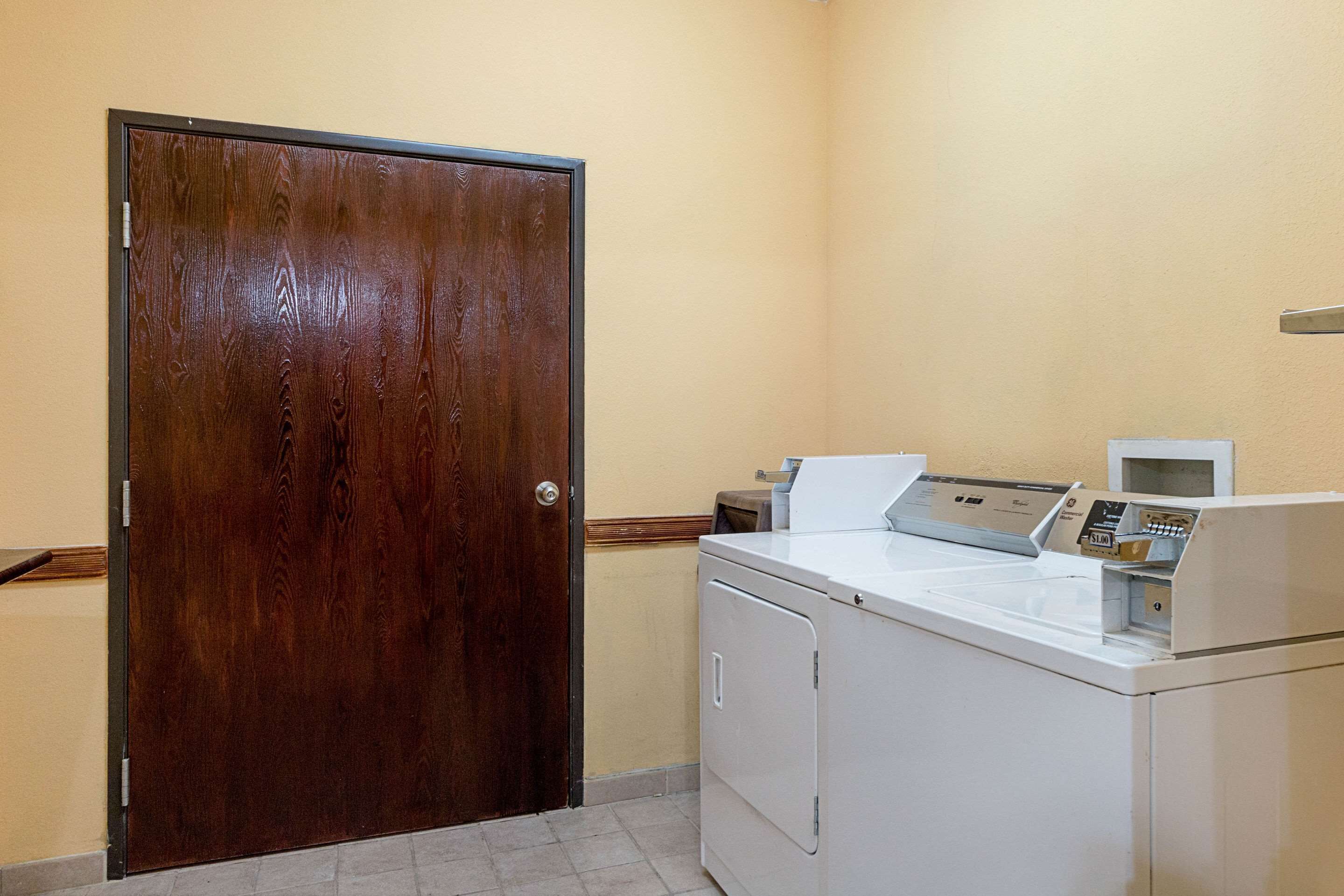 A laundry room with a wooden door, a white washing machine, and a dryer.