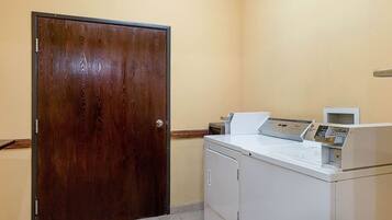 A laundry room with a wooden door, a white washing machine, and a dryer.