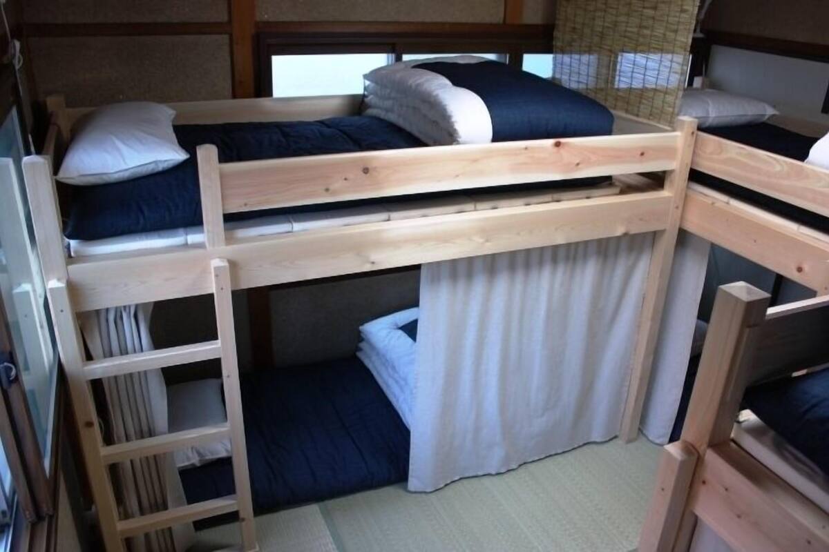 A bunk bed room with a ladder, a curtain, and a window.