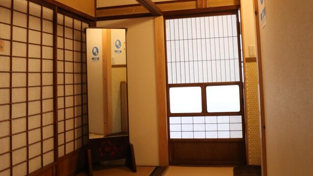 A traditional Japanese room with tatami flooring, wooden beams, shoji screens, and a sliding door. - Guesthouse Tomaru (Takayama)
