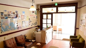 A cozy lobby with a wooden bench, striped sofas, and a reception desk. - Guesthouse Tomaru (Takayama)