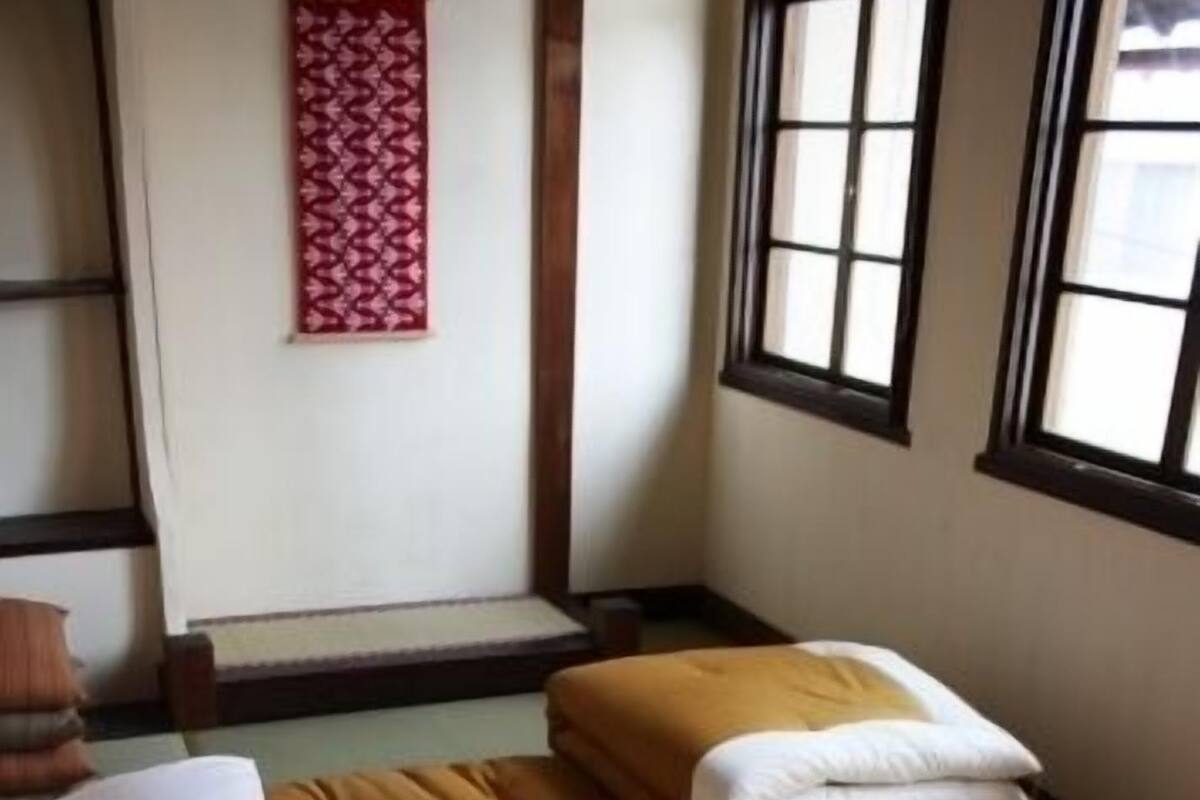 A room with a bed, pillows, a window, and a wall decoration.