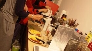 A person standing at a counter with food items and a weighing scale. - Guesthouse Tomaru (Takayama)