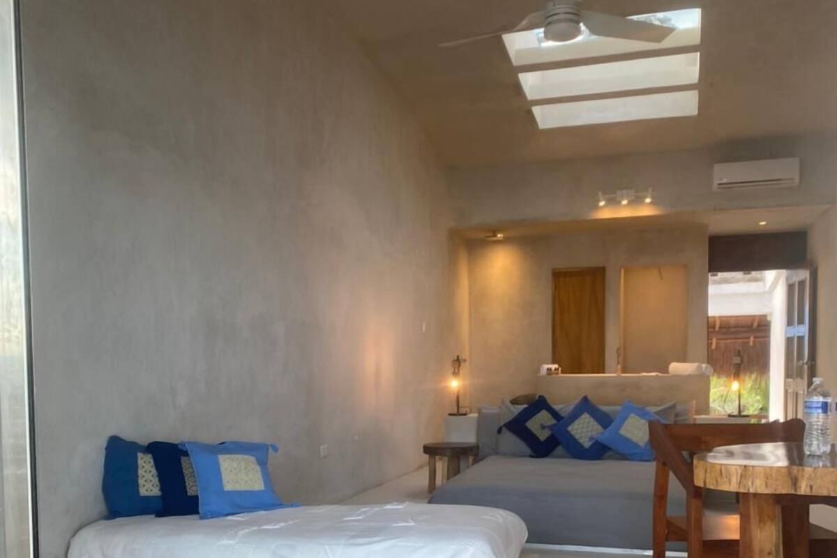 A room with a bed, a wooden table, and a ceiling fan.