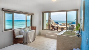 Una habitación con un ventanal grande con vistas al mar, una bañera y una mesa con una silla.