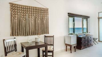 Un comedor con mesa y sillas de madera, un adorno en la pared y vista al mar a través de una ventana.
