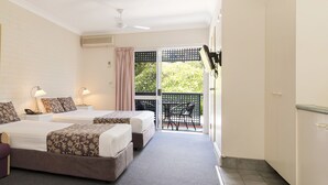 A hotel room with two beds, a purple sofa, a painting on the wall, and a balcony with a chair. - Benson Court Motel (Toowong)