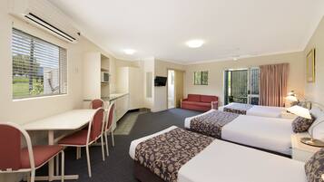 A hotel room with two beds, a desk, a chair, and a TV.
