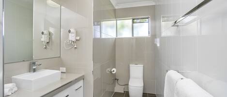 A modern bathroom with a large mirror, a sink, a toilet, and a shower area.