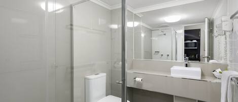 A modern bathroom with a glass-enclosed shower, a white toilet, a sink with a mirror, and a towel rack.