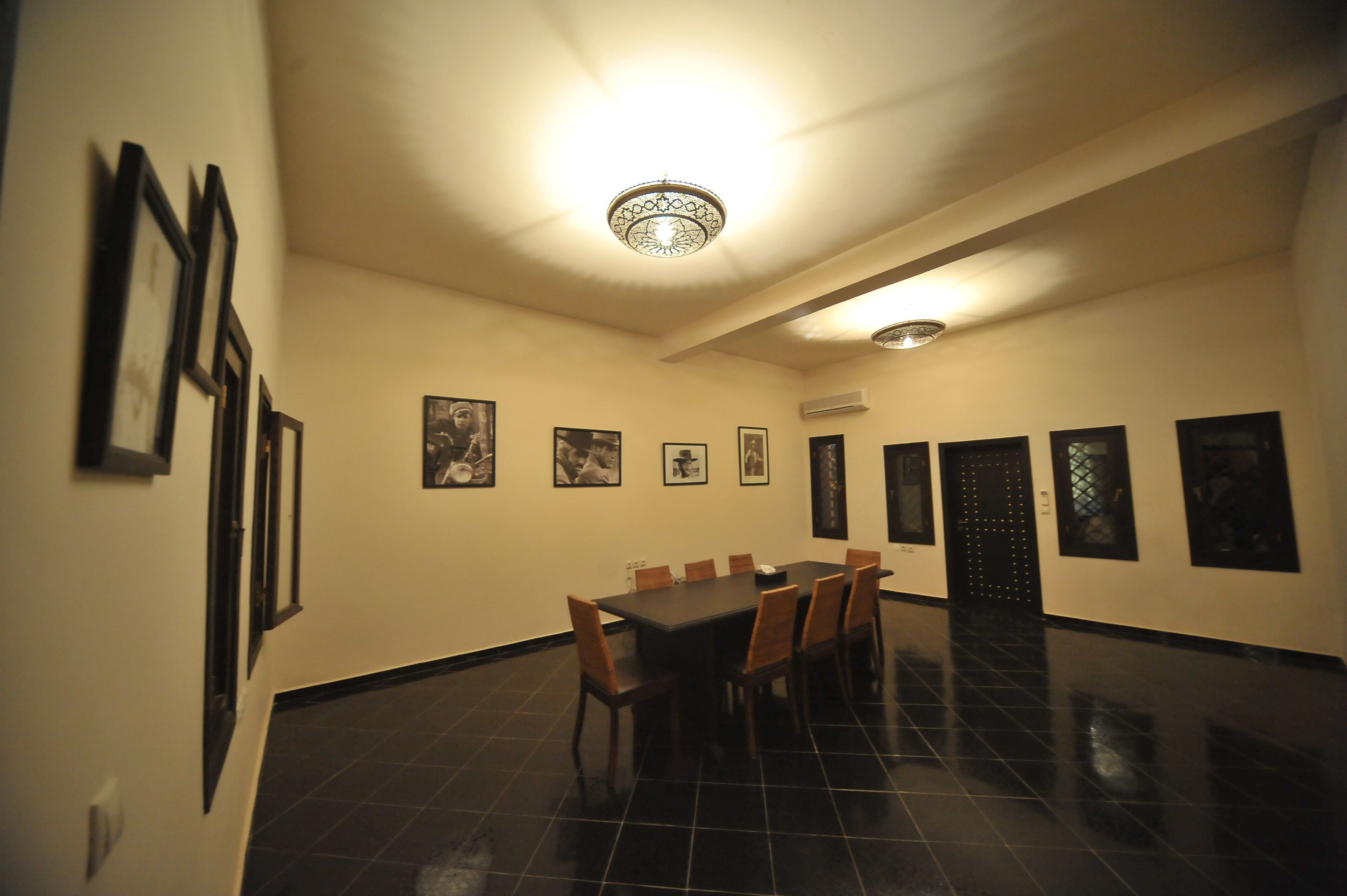 Una sala de conferències amb una taula llarga, cadires, quadres a les parets i un lluminari al sostre.
