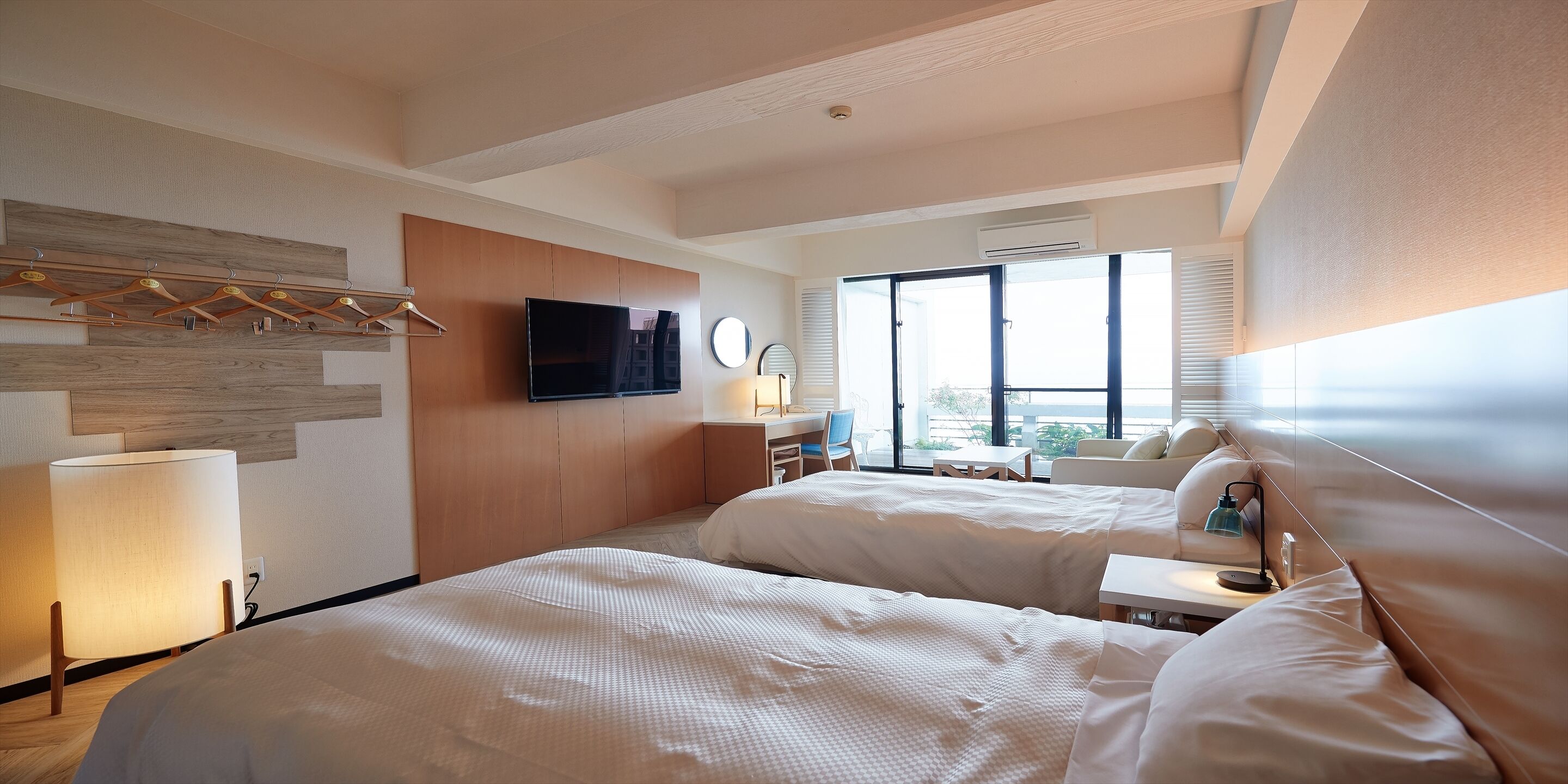 Una habitación de hotel con dos camas, televisión, escritorio y un ventanal grande.