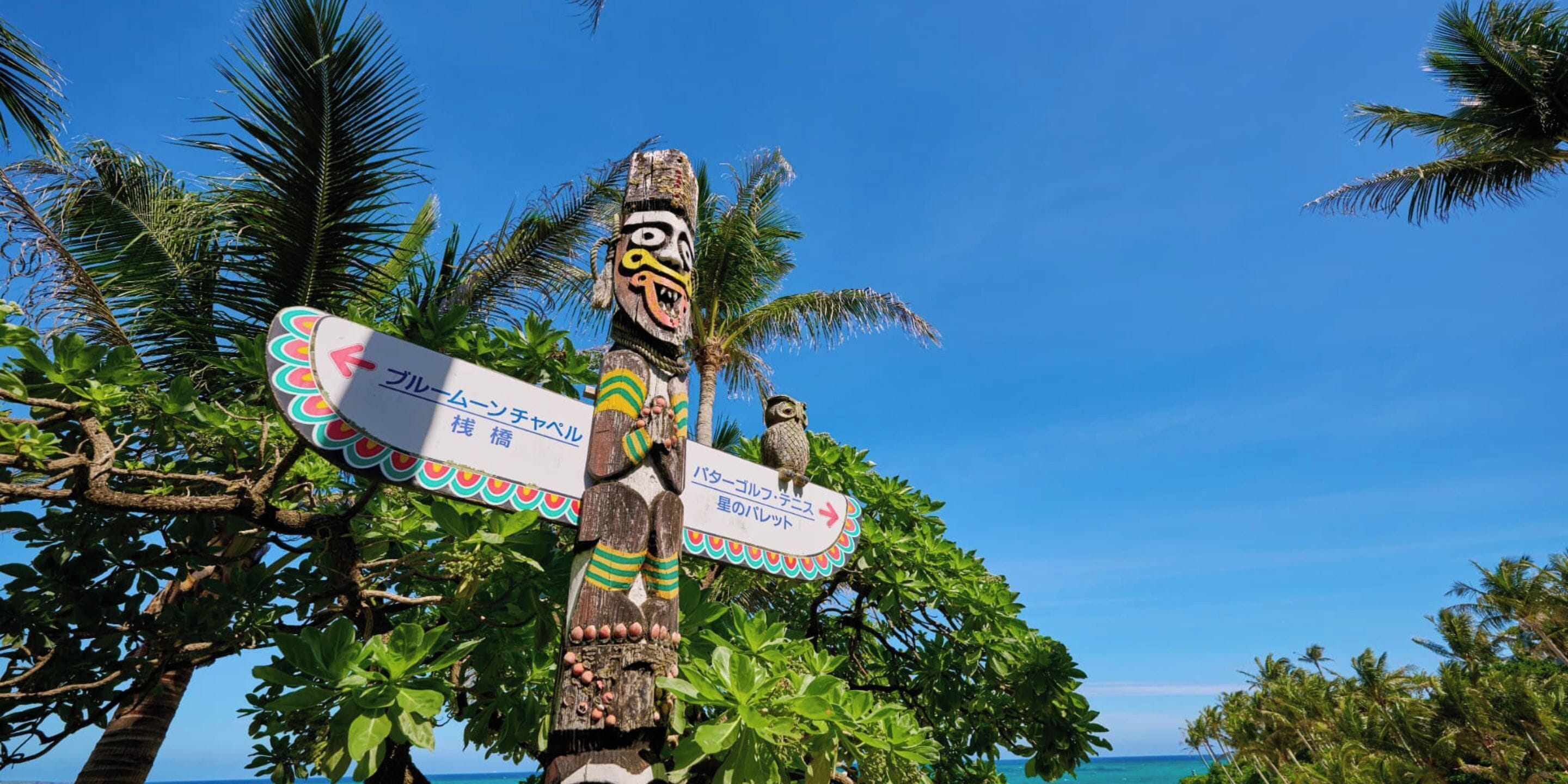 A wooden totem with a carved face and a signboard.