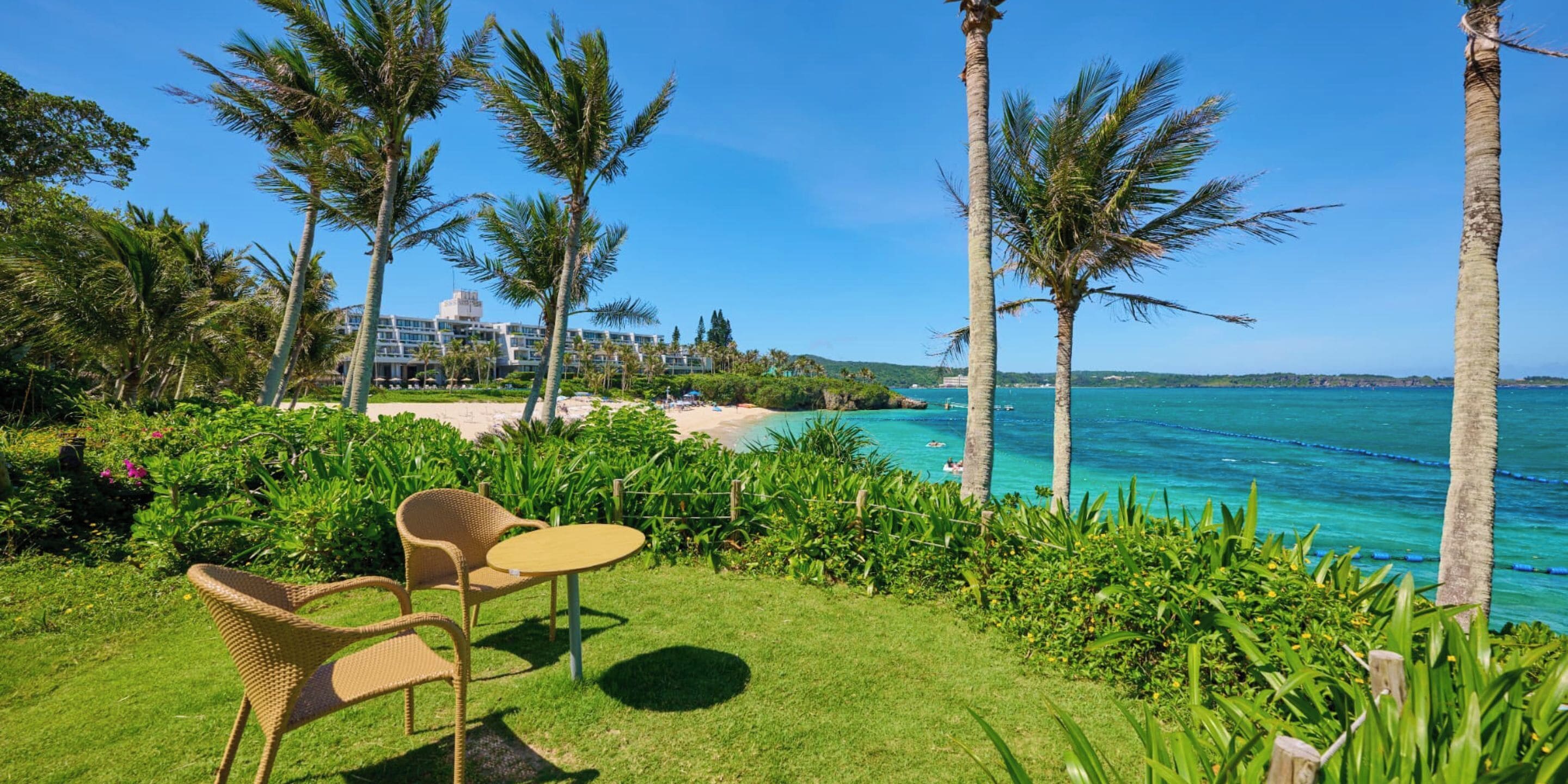 A tropical resort with a pool, palm trees, and a view of the ocean.