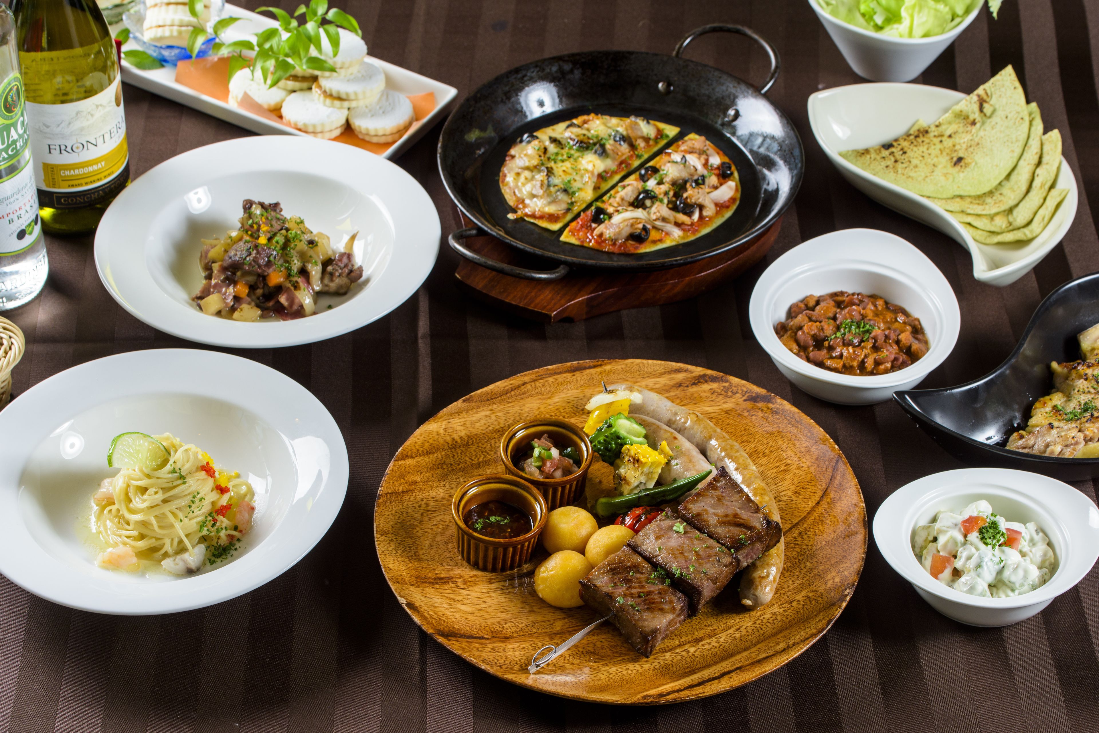 A variety of dishes including pasta, steak, and a hot pan.