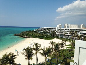 A beachfront hotel with multiple floors, a sandy beach, and palm trees. - Palace in Moon Beach (Onna)