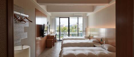 A modern hotel room with two beds, a desk, and a balcony with a view.