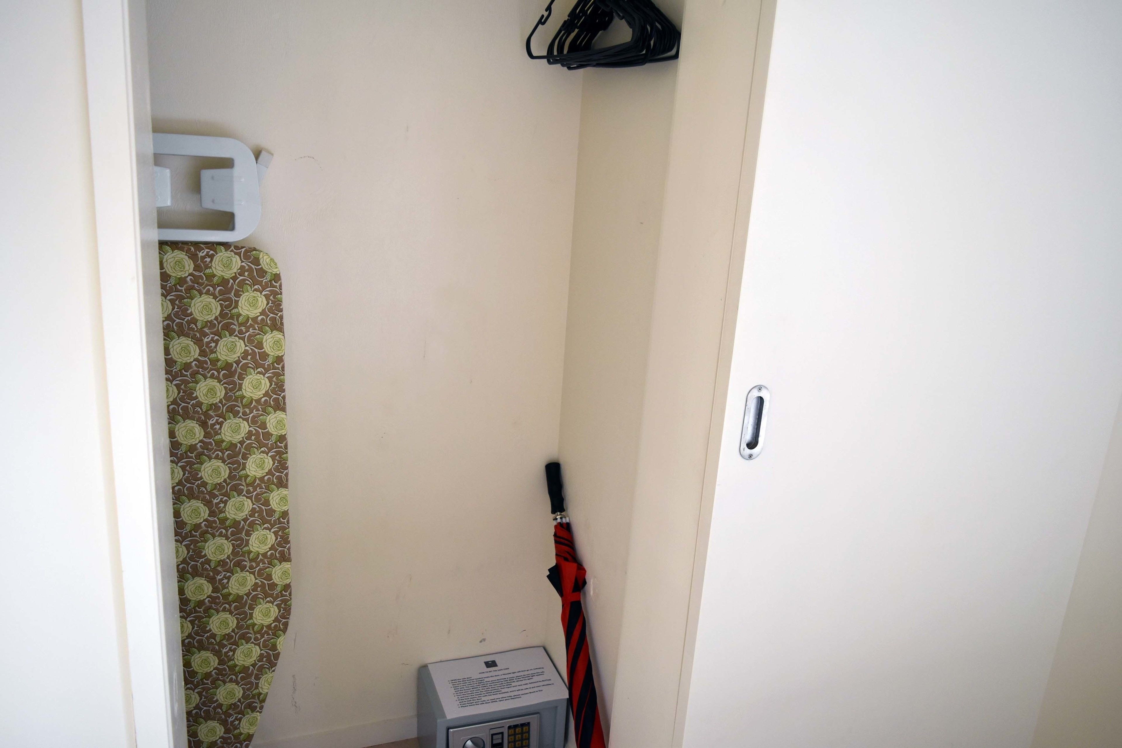 A narrow hallway with a patterned curtain, a black and red umbrella, and a small device on the floor.