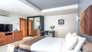 Une chambre moderne avec un grand lit, une télévision, des meubles en bois et un bureau.