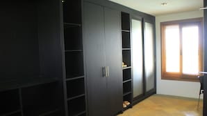Une pièce avec une grande armoire noire, une fenêtre avec des stores et un sol carrelé.
