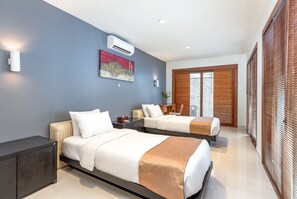 A modern hotel room with two beds, a dark cabinet, a painting, and a large window with blinds. - Hening Jimbaran (Jimbaran)