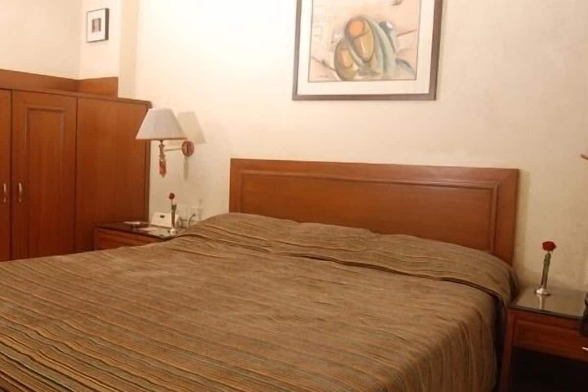 Un dormitorio con cama de madera, mesita de noche con lámpara y armario.