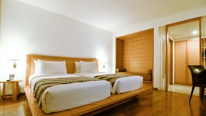 Una cama doble con cabecera de madera, una mesita de noche y una silla en una habitación moderna con suelo de madera y un ventanal grande.