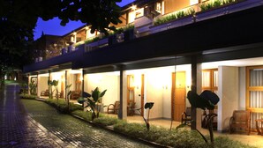 Un hotel con un espacio al aire libre techado, varias habitaciones y un camino pavimentado.