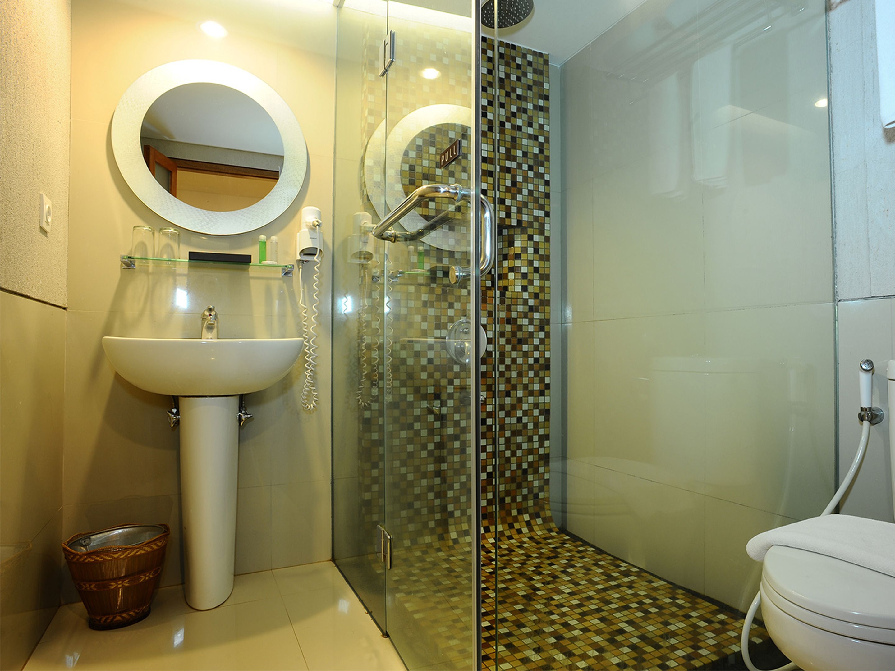 A bathroom with a sink, mirror, toilet, and a shower with a glass door.