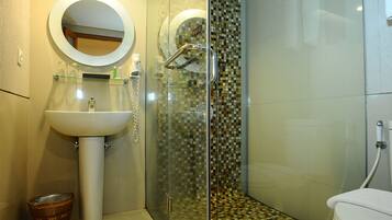 A bathroom with a sink, mirror, toilet, and a shower with a glass door.