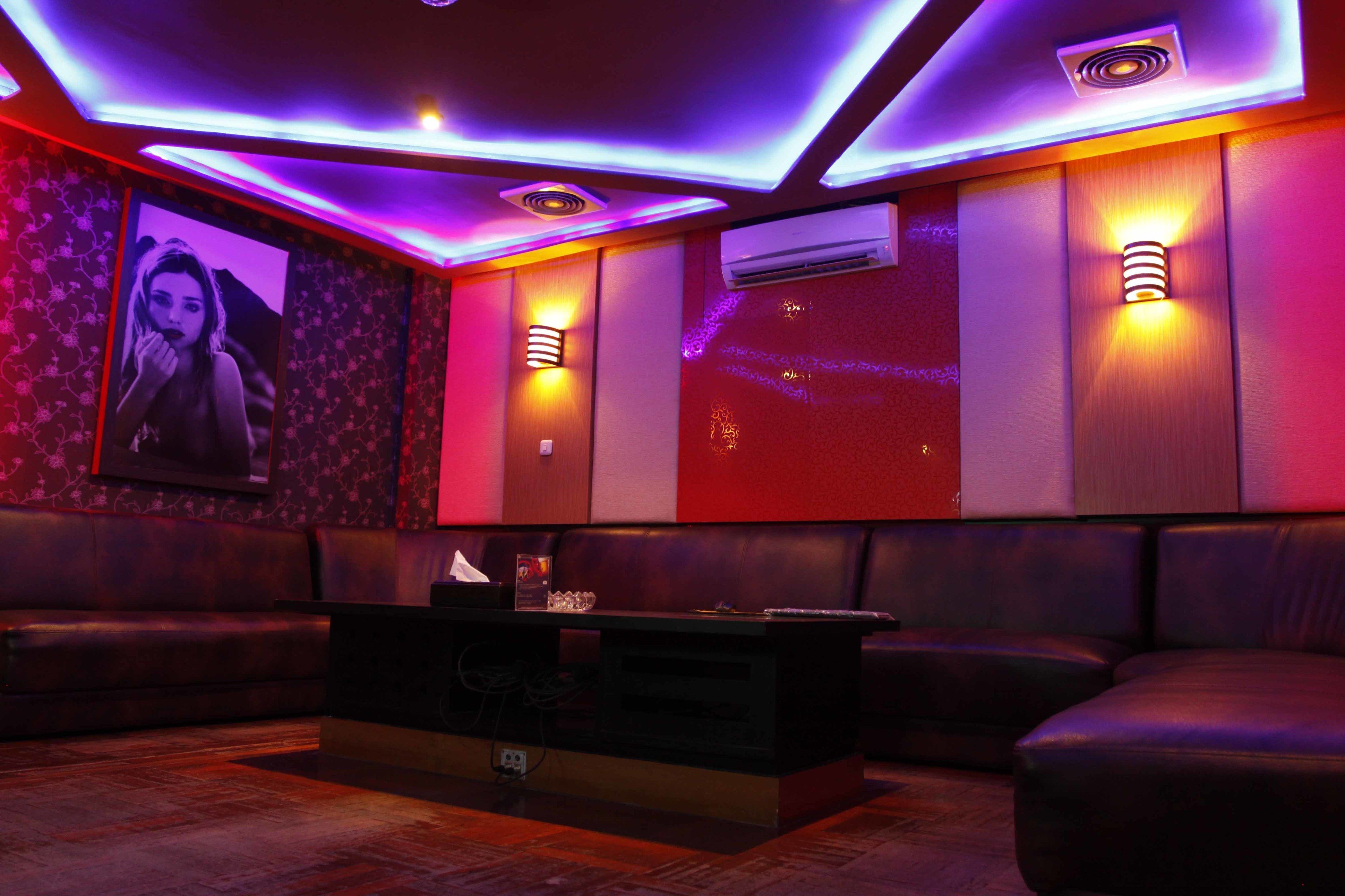 A modern lounge area with leather seating, ambient lighting, and a large screen displaying an image.
