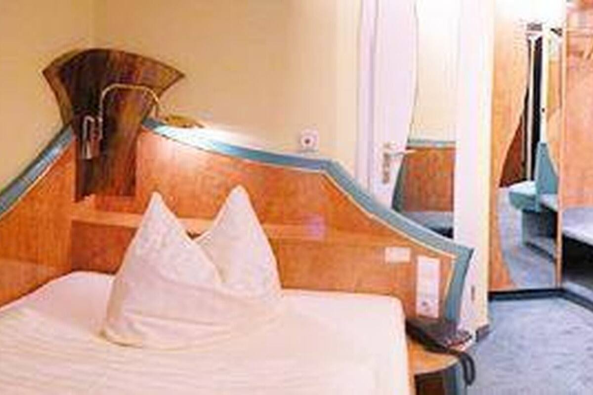 Una habitación de hotel con cama, una silla y zona de ducha.