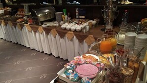 A buffet with various food items and beverages, including a large bowl of pink dessert, a pitcher of orange juice, and several containers of yogurt. - City Hotel Essen (Essen)