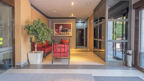 A modern hotel lobby with a red sofa, a large potted plant, and a framed artwork on the wall. - Hotel Hidalgo (Esquivias)