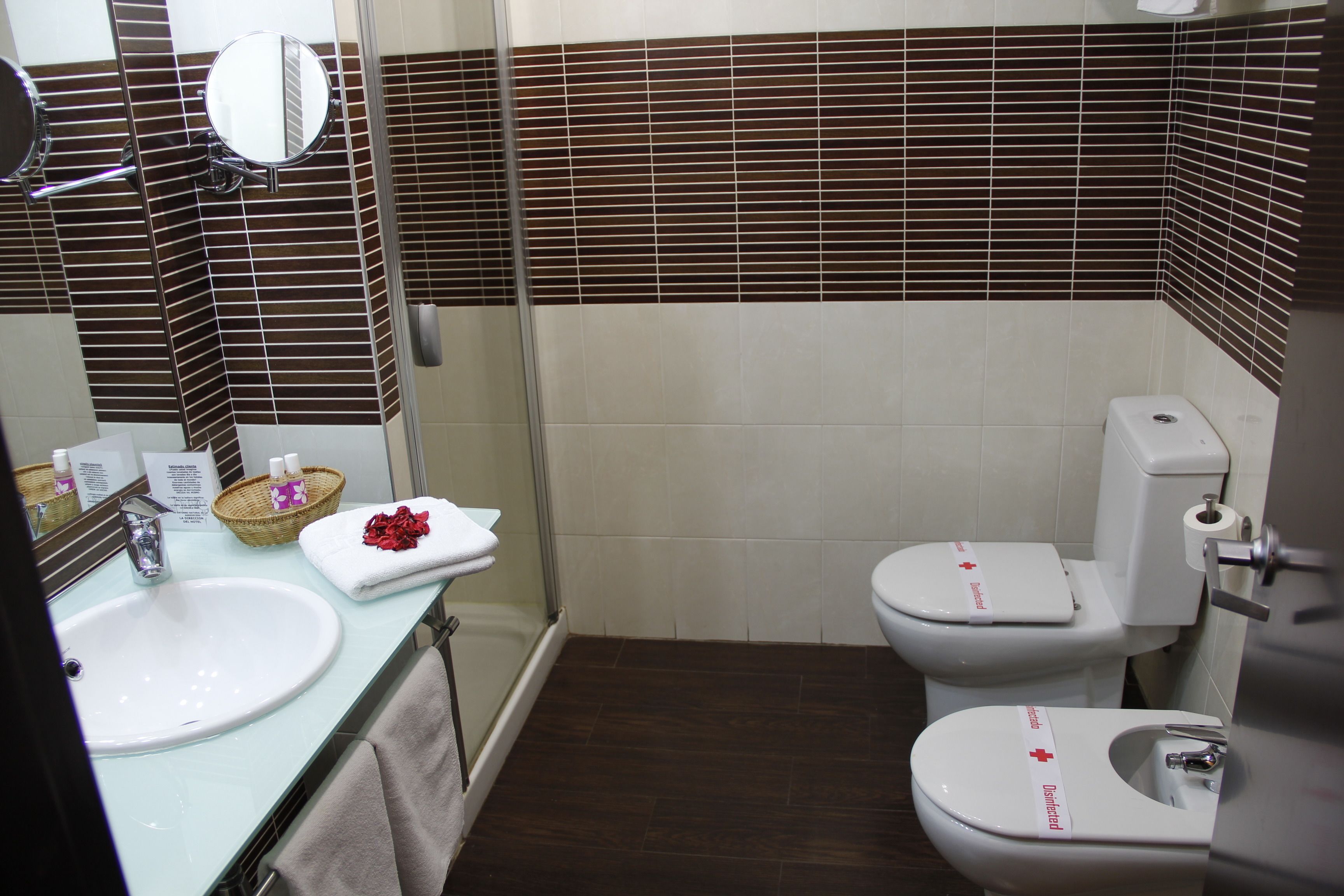 A bathroom with a sink, mirror, and two toilets.