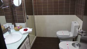 A bathroom with a sink, mirror, and two toilets.