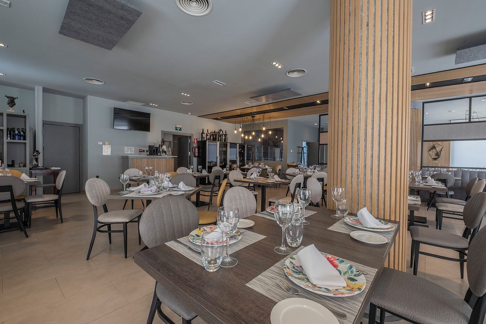 Een modern restaurant met meerdere eettafels, stoelen en een bar.