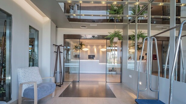 A modern reception area with a reception desk, seating area, and a staircase with glass railings. - Hotel Hidalgo (Esquivias)