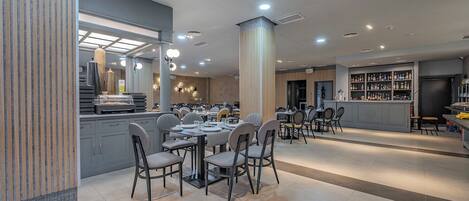 Um restaurante moderno com área de jantar central, um bar e uma cozinha visível ao fundo.
