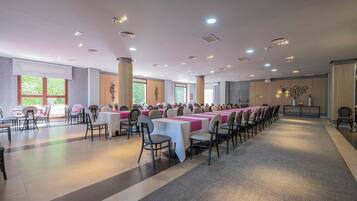 Una sala conferenze con diversi tavoli e sedie, ampie finestre e un design moderno del soffitto.