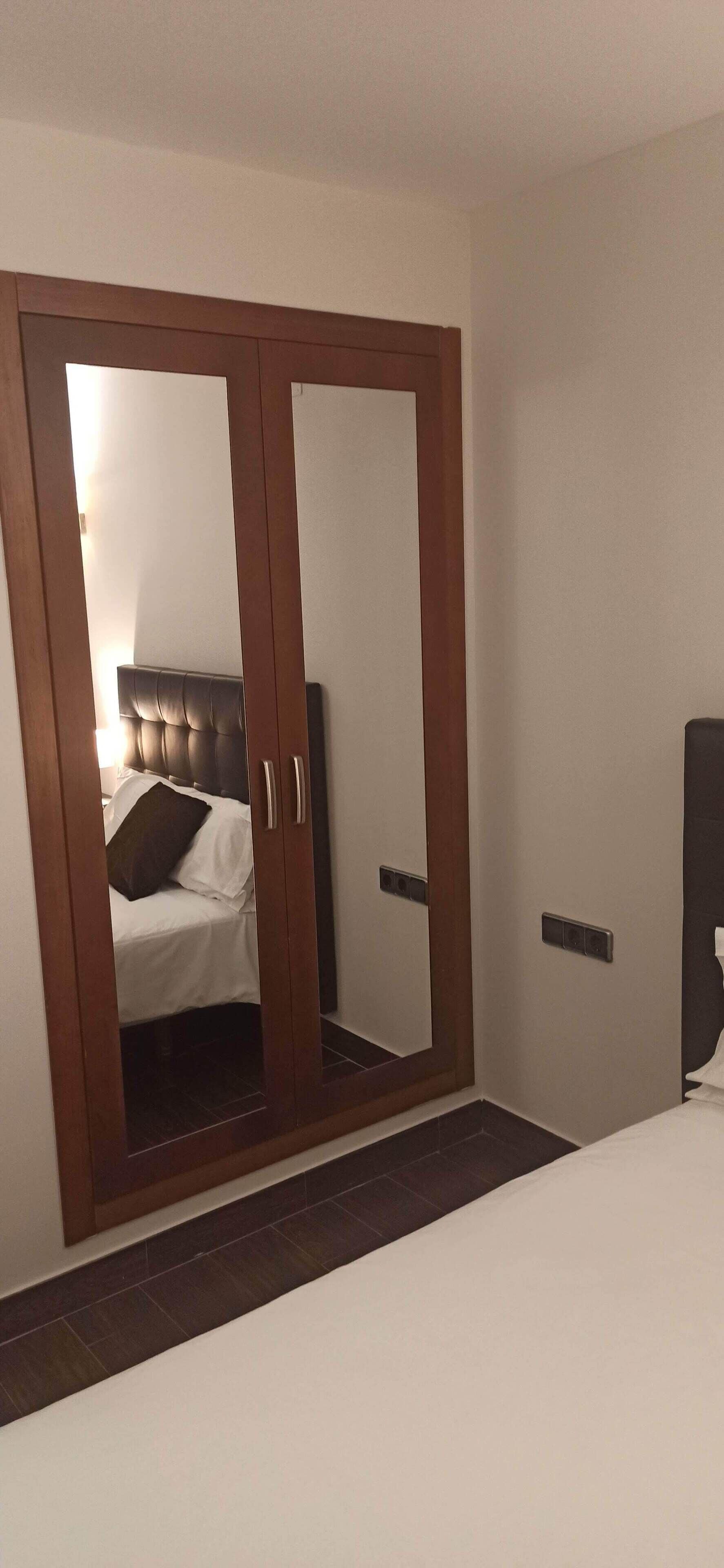 Un dormitorio con un armario grande, una cama y una mesita de noche.