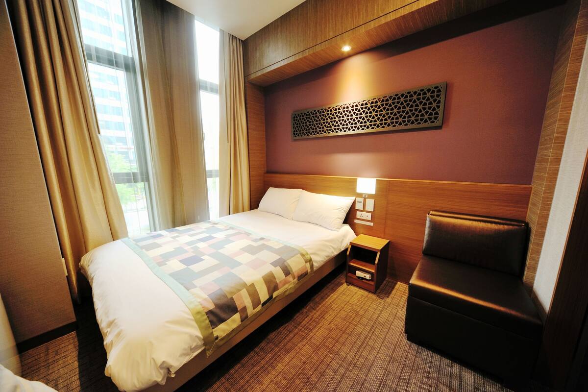 Habitación de hotel con una cama grande, una mesita de noche, una silla y un panel decorativo en la pared.