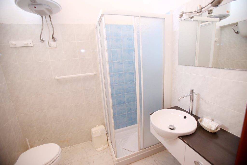 Et badeværelse med brusebad, toilet, vask og spejl.