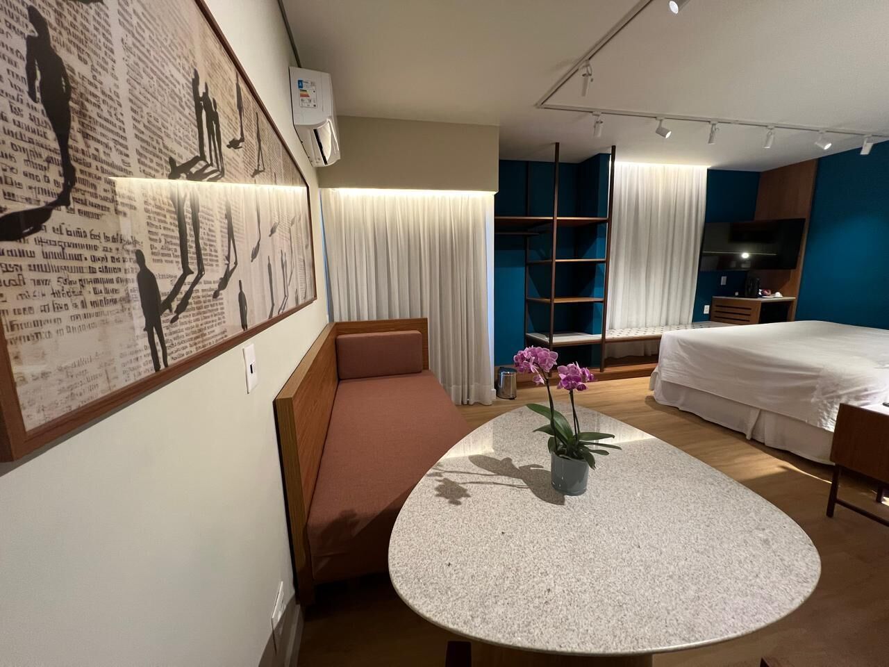 Una habitación de hotel con una mesa redonda, un sofá, una cama y un televisor.